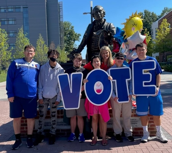 Students in front of the George Mason statue holding up letters spelling VOTE